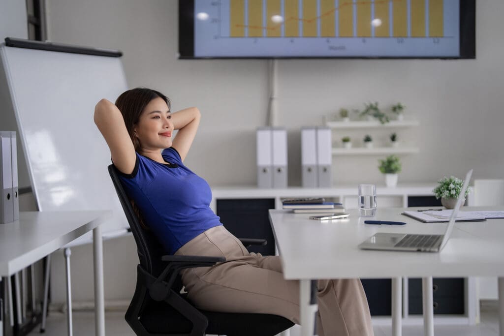 A woman smiling and laying back in her office chair.